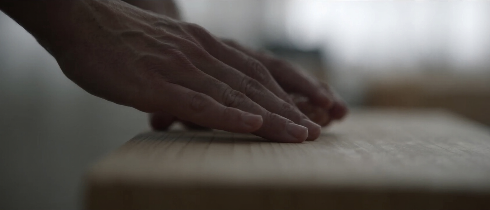 The chef's hands pressing nigiri over the pale hinoki counter