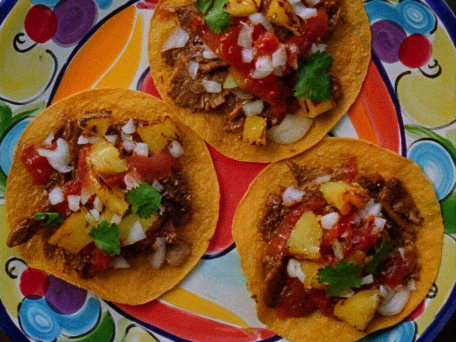 Three al pastor tacos with charred pineapple on a talavera plate