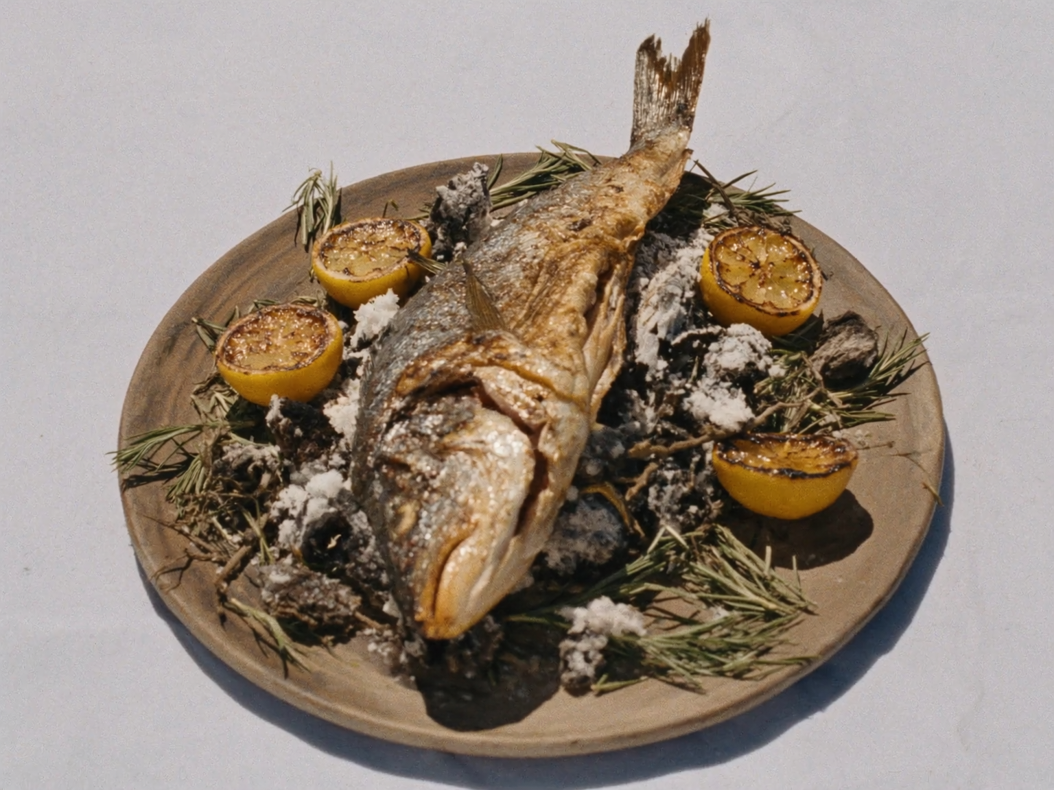 Whole grilled sea bass over vine embers with charred lemon