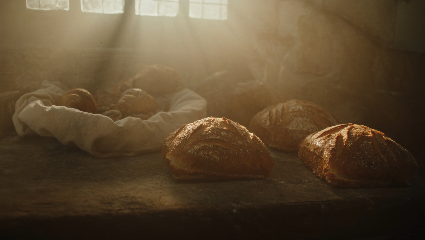 Crusty sourdough loaves dusted with flour on a wooden counter in warm morning light